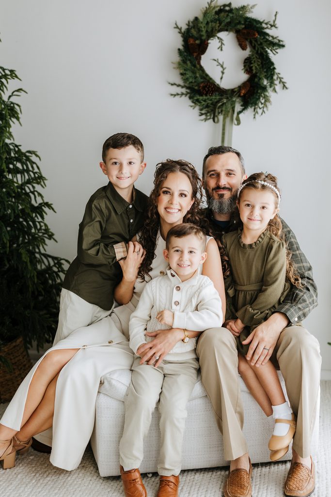 Family cuddling on neutral seating during a Christmas mini session in Louisville, KY