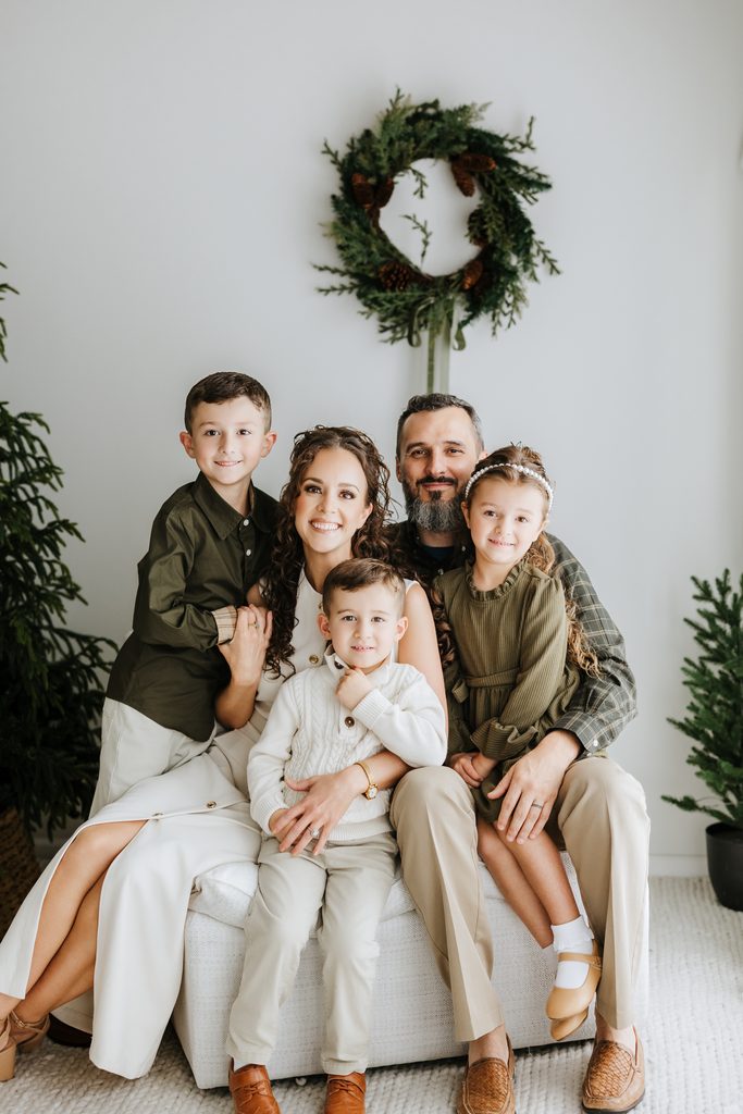 Family cuddling on neutral seating during a Christmas mini session in Louisville, KY