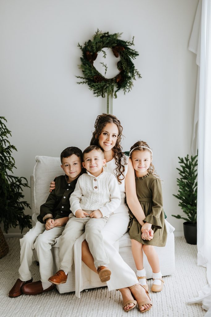Family cuddling on neutral seating during a Christmas mini session in Louisville, KY
