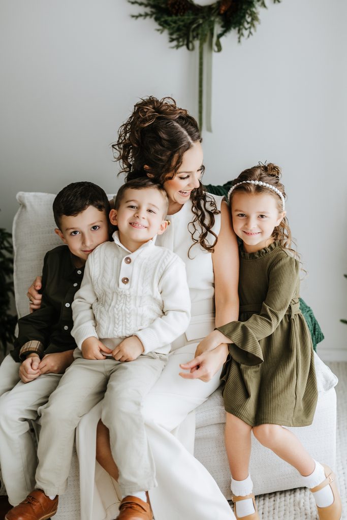 Family cuddling on neutral seating during a Christmas mini session in Louisville, KY