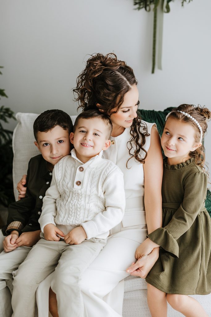 Family cuddling on neutral seating during a Christmas mini session in Louisville, KY