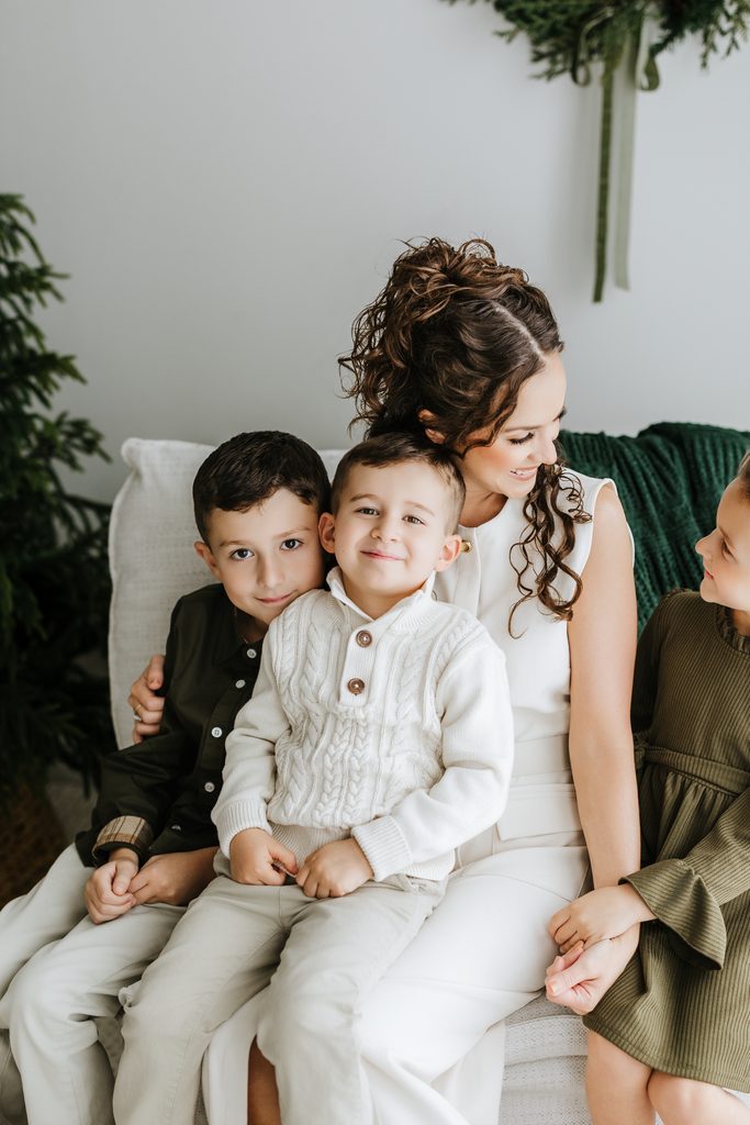 Family cuddling on neutral seating during a Christmas mini session in Louisville, KY