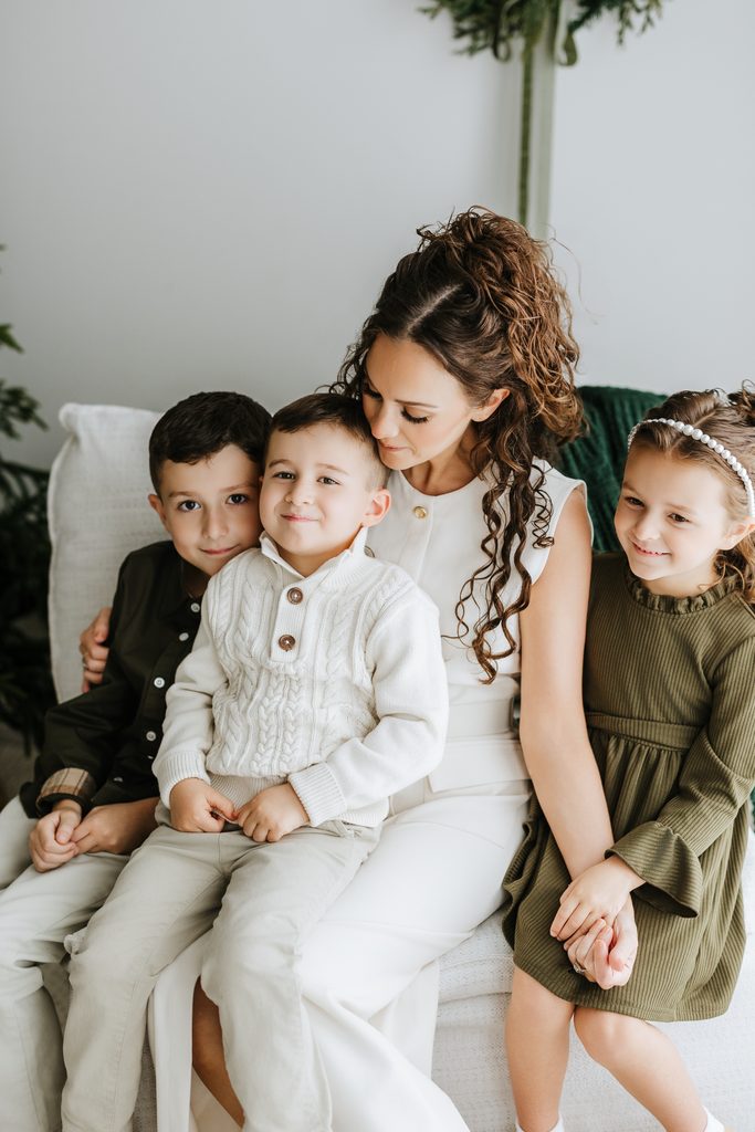 Family cuddling on neutral seating during a Christmas mini session in Louisville, KY
