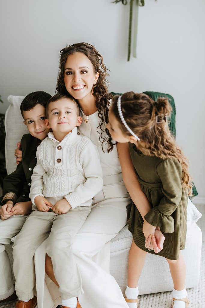 Family cuddling on neutral seating during a Christmas mini session in Louisville, KY