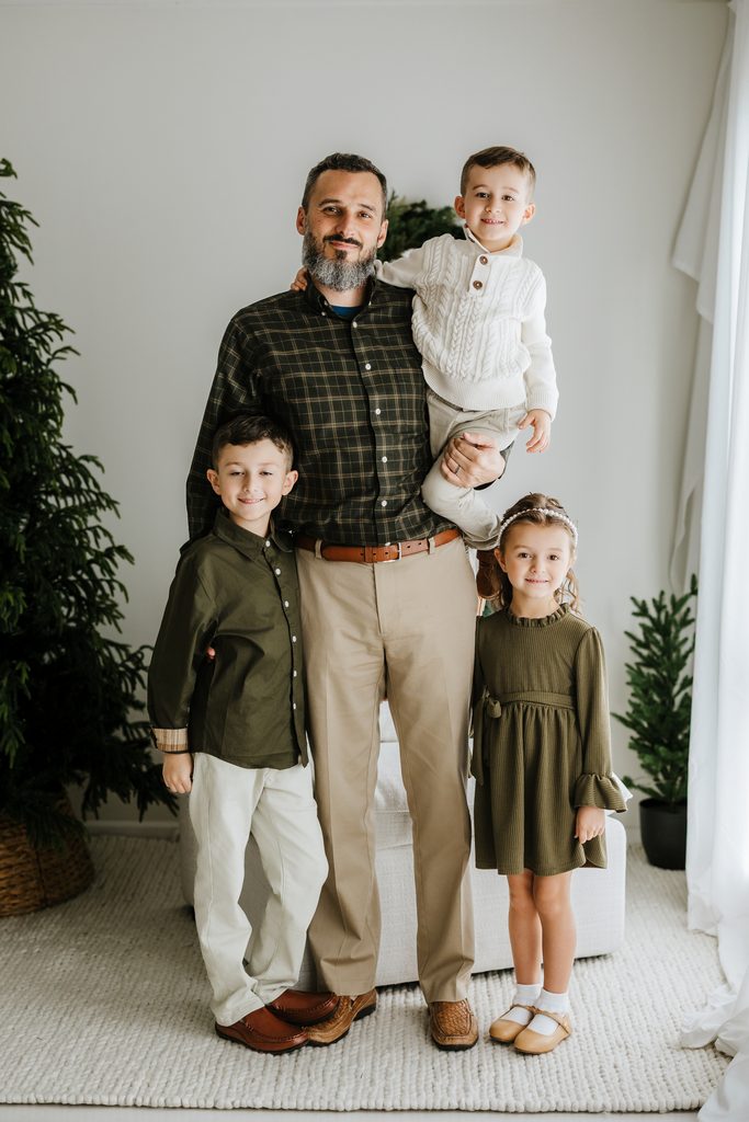Family cuddling on neutral seating during a Christmas mini session in Louisville, KY