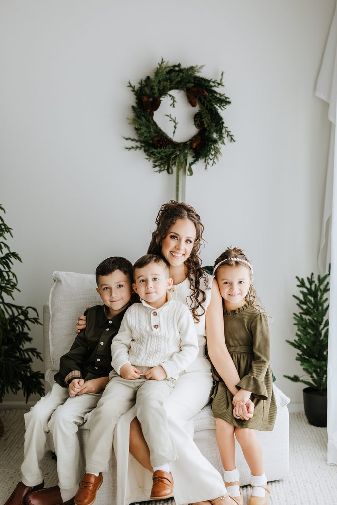Family cuddling on neutral seating during a Christmas mini session in Louisville, KY