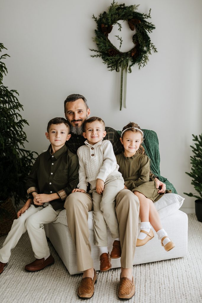 Family cuddling on neutral seating during a Christmas mini session in Louisville, KY