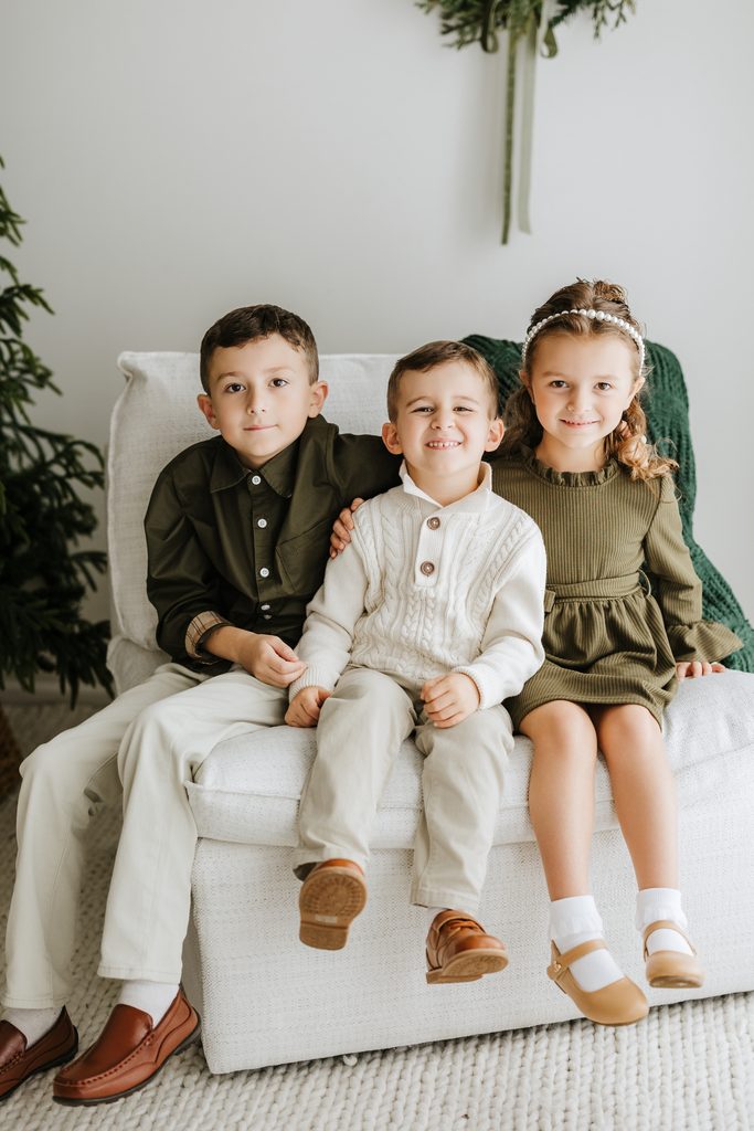 Family cuddling on neutral seating during a Christmas mini session in Louisville, KY