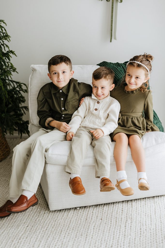 Family cuddling on neutral seating during a Christmas mini session in Louisville, KY