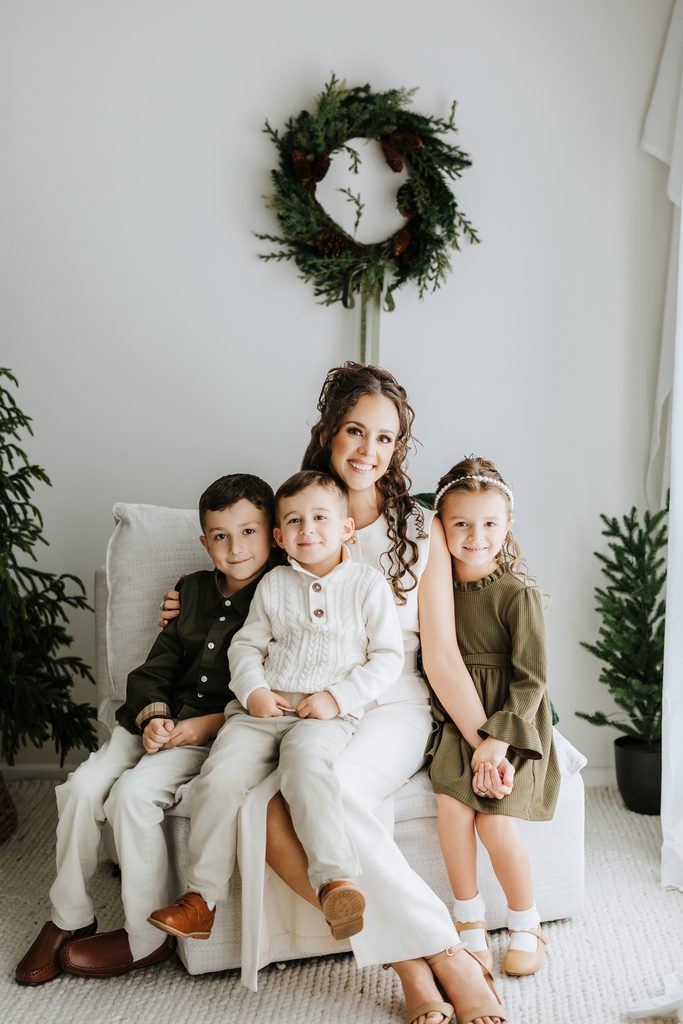Family cuddling on neutral seating during a Christmas mini session in Louisville, KY