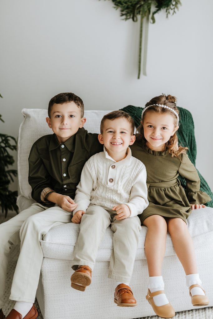 Family cuddling on neutral seating during a Christmas mini session in Louisville, KY