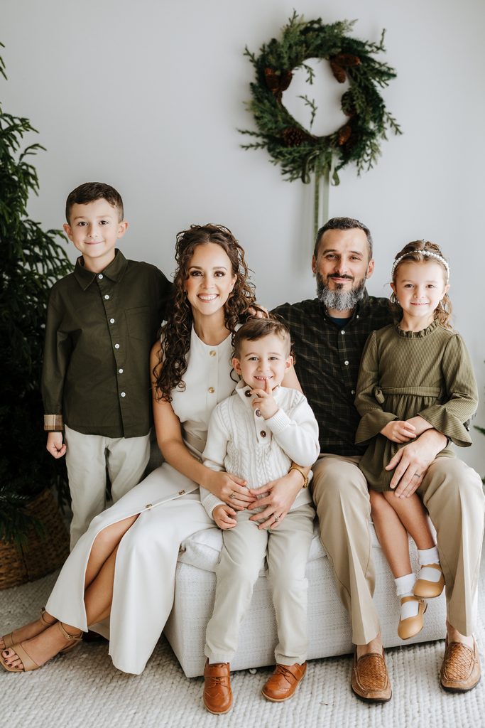 Family cuddling on neutral seating during a Christmas mini session in Louisville, KY