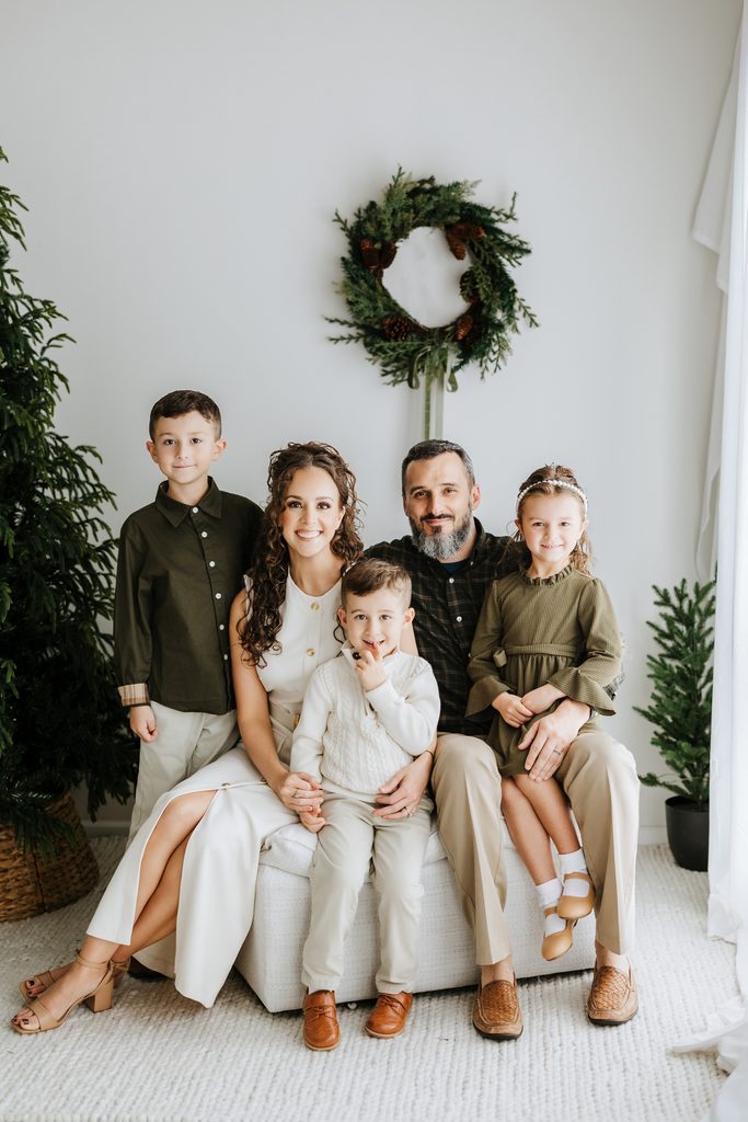Family cuddling on neutral seating during a Christmas mini session in Louisville, KY