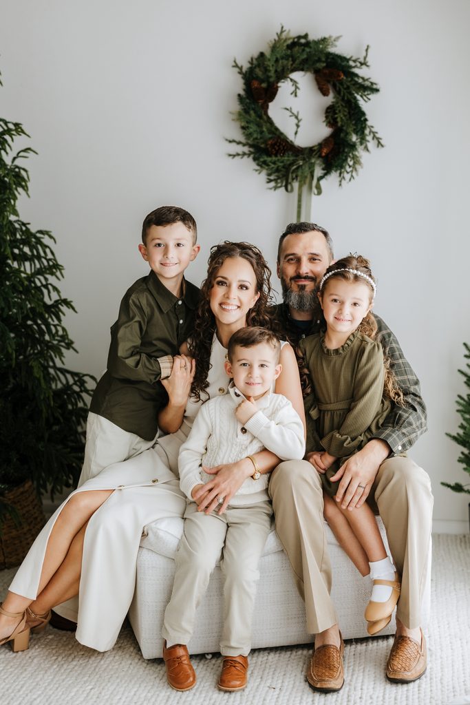 Family cuddling on neutral seating during a Christmas mini session in Louisville, KY